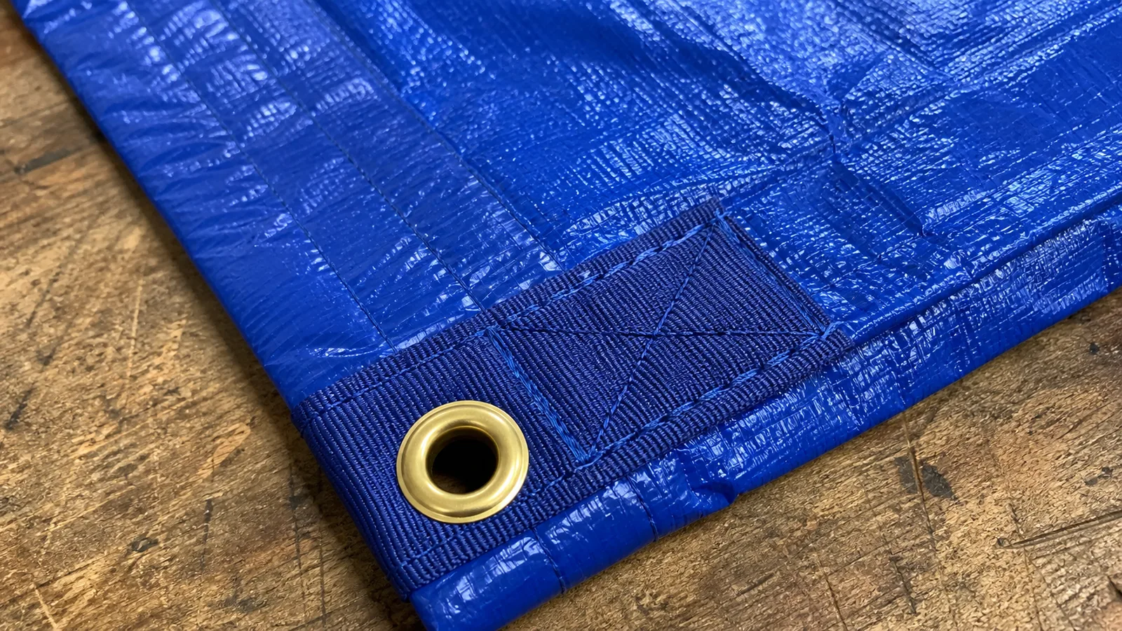 Reinforced PVC tarp corner showing hem, grommet, and webbing details